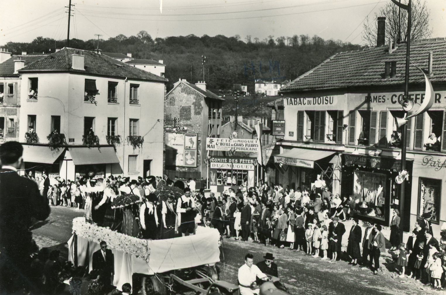 Carte postale (sans date) du défilé de chars pour les Fêtes du Muguet sur l’avenue Roger Salengro, au niveau du quartier du Doisu.
